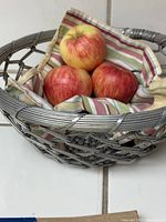 Top-view of the woven aluminum fruit basket bowl with cloth liner and apples inside, showing detailed weave and colors of liner.