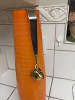 Ice serving tongs arranged on an orange textured container, highlighting the fruit/citrus decorative element at the end.