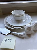 Photo of stacked white bone china plates and bowls with leaf pattern, salt and pepper shakers shaped like birds, and matching cake server.
