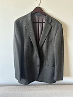Front view of Brooks Brothers men's wool cashmere suit jacket on hanger against white wall.