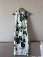 Front view of sleeveless dress on hanger with floral print and fitted silhouette.