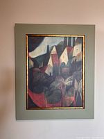 Frontal photo of the framed expressionism painting depicting a town with trees and warm colors.