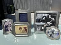 All six photo frames grouped together outdoors on glass table, showing size and shape variety