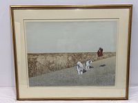 Framed print showing two white dogs and a person near a textured brown wall under a light sky.