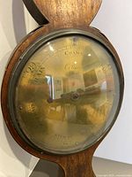 Close up of the round barometer dial with glass cover showing readings and maker's mark C. Bianchi