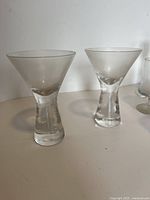 Close-up of two clear stemmed flute glasses on a white surface
