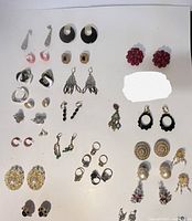 Top-down photo of the assorted vintage and modern jewelry lot showing various earrings and rings laid out on a white background.