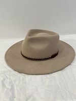Front view of beige wool fedora hat showing decorative woven band and shape of the brim and crown.