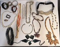 Full view of multicolor mixed material jewelry lot featuring necklaces and bracelets spread on a white surface