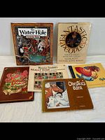 Seven children's illustrated books displayed flat showing colorful, fantasy-themed covers including 'The Water Hole' and 'Really Rosie'