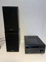 Denon CD receiver with two Denon speakers stacked vertically, all black with cloth speaker covers visible