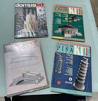 Four boxed Domus model kits on a white surface, including Torre di Pisa, Tempietto di San Pietro, La Rotonda, and Ponte di Rialto. Kits are sealed in original packaging with clear plastic wrap.