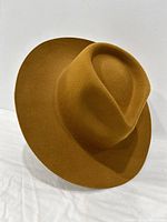 Side angled view of mustard yellow formal hat showing its wide brim and creased top.