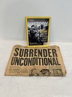 Photo of National Geographic History magazine standing behind a folded Toronto Daily Star newspaper with headline 'Surrender Unconditional'