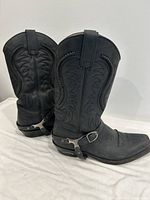 Side view of both black leather Sendra western boots showing stitching, harness strap, buckle, and overall shape.