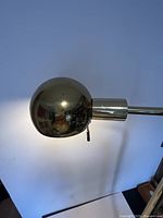 Close-up of the brass floor lamp sphere-shaped lamp head attached to vertical brass pole.