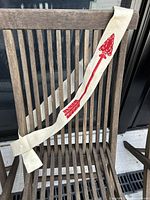 Full length view of the cream felt sash with red arrow design draped on wooden chair.