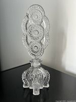 Front view of the clear art glass perfume bottle with ornate cut glass stopper.
