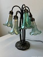Lamp off showing six green art glass lily-shaped shades on curved metal arms and decorative metal base.