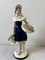 Front view of the Royal Dux porcelain lady figurine showing the detailed dress, bonnet, and flower baskets.