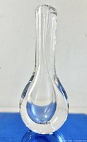 Clear glass teardrop vase with Kosta Boda label facing front, showing shape and clarity.