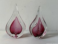 Front view of both clear glass teardrop paperweights showing internal red-purple heart motifs and signed by Marian Pyrcak.