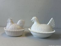Pair of vintage milk glass hen on nest condiment holders displayed side by side
