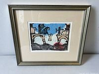 Frontal view of framed mixed media artwork showing figures on arches above stylized water with Hebrew manuscript details.