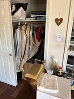 Closet interior showing hanging garments and electronics on top shelf