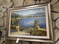 Front view of framed acrylic painting showing waterfront village and mountains.