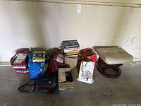 Wide view of all bags, stacks of books, boxes, and a beige cushioned stool on the right.