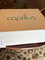 Closed white box with green Capillus logo on lid