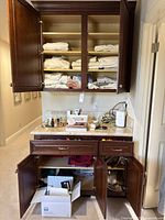 Overview of open cabinets with folded linens and countertop displaying lot items