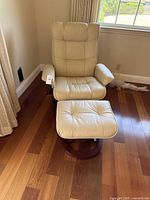 Front view of cream leather swivel chair with ottoman on hardwood floor