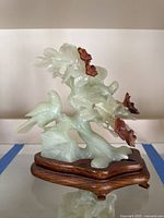 Front view of jade sculpture on wooden base showing two birds and floral branches