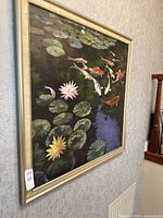 Angled full view of framed oil painting showing koi fish and lotus on canvas