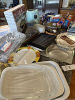Full view of kitchen items on countertop including Bella air fryer, Chef's pan box, glass and ceramic bakeware including CorningWare, and metal pans and trays.