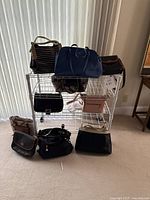 Overview of ten purses displayed on white metal shelving unit