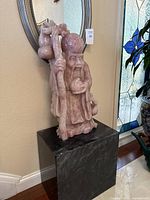 Full front view of rose quartz deity sculpture on black stone base