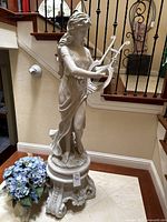Full view of statue and pedestal on marble floor under stair railing