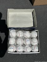 Box containing 12 individually wrapped MacGregor baseballs, arranged in three rows of four.