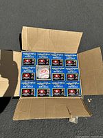Open cardboard box containing 12 Rawlings Official ASA Softballs in individual blue boxes, one softball visible outside the box.