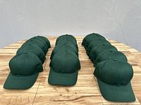 Front view showing three rows of hunter green baseball caps arranged symmetrically on a wooden surface.