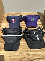 Stack of visors showing logos for Minnesota Twins, Arizona Diamondbacks, Chicago White Sox and several black mesh non-logo visors.