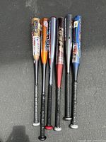 Full view of six aluminum baseball bats with grip tape handles, varying colors and brands.