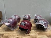 Six Rawlings burgundy batting helmets on display, five still in plastic wrapping.