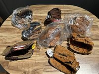 Photo of 8 baseball gloves on wooden table, some wrapped in plastic, some loose showing Franklin branding