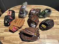 Top view photo showing all 8 gloves arranged on a wooden table, various colors and brands visible.