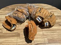 Group of eight Franklin brand leather baseball gloves, six in plastic wraps, two unpackaged, laid on a wooden table.