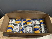 Box containing approximately 16 pairs of blue and yellow striped soccer socks in original packaging, aligned side-by-side.